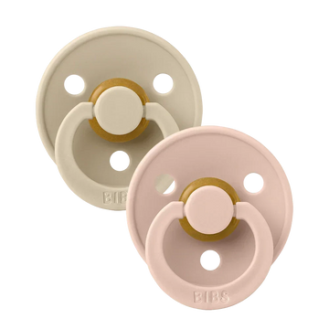 Two round latex baby pacifiers, blush pink and vanilla beige with gold accents