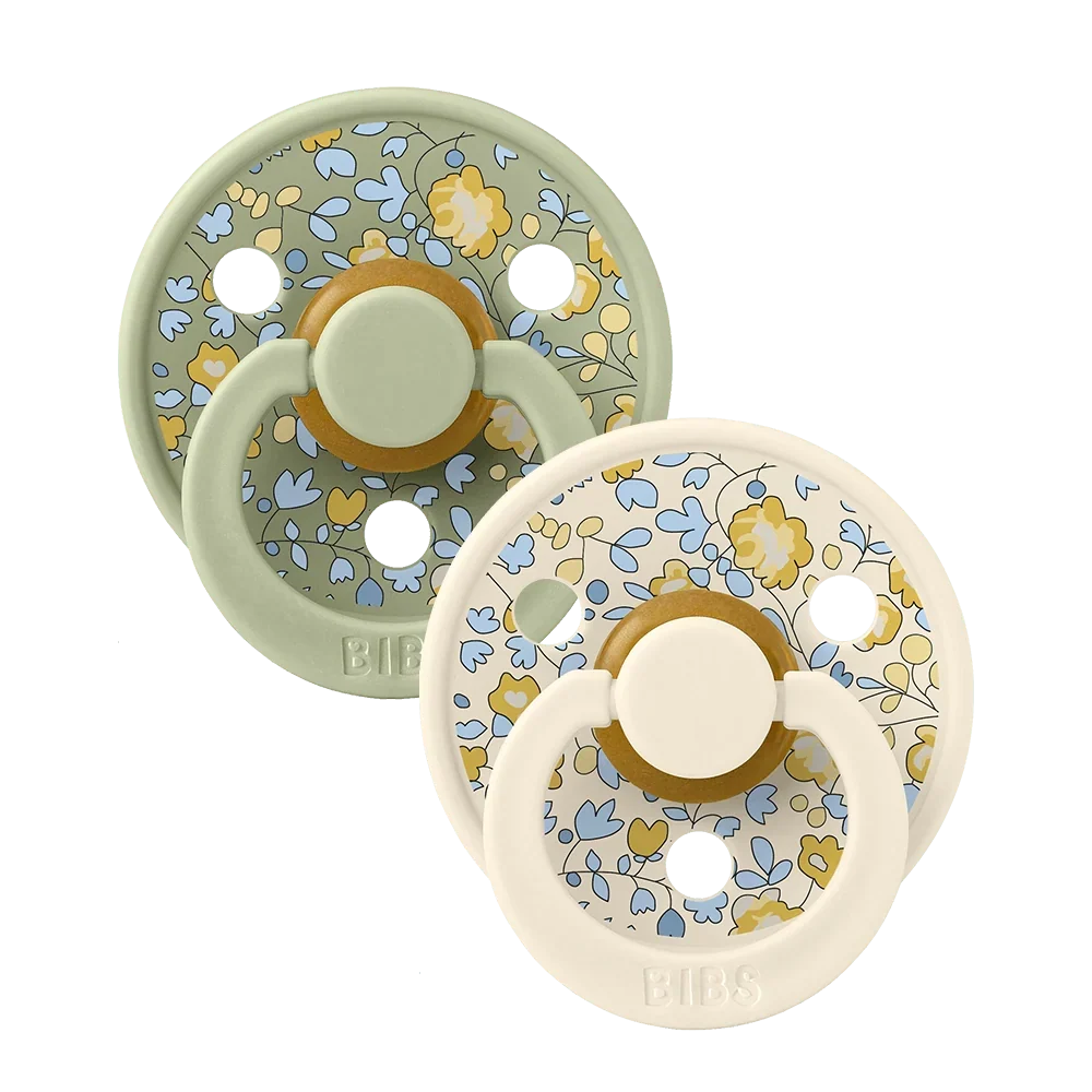 Two sage-mixed floral latex baby pacifiers, round shield with yellow ring detail