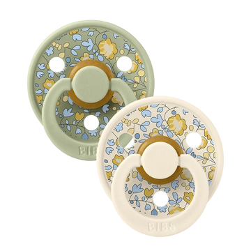 Two sage-mixed floral latex baby pacifiers, round shield with yellow ring detail