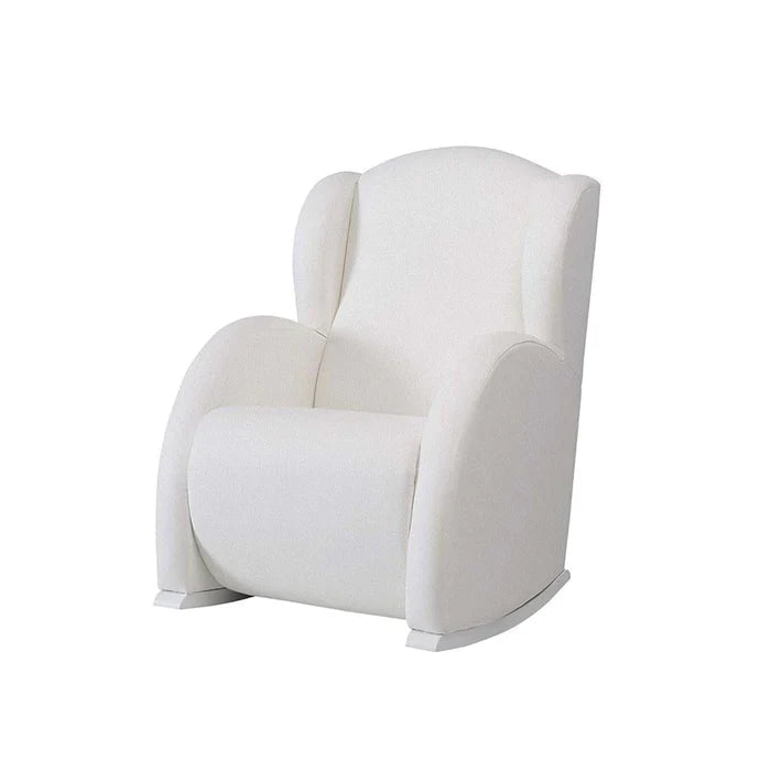 White armchair in a room with a bookshelf and decorative items.