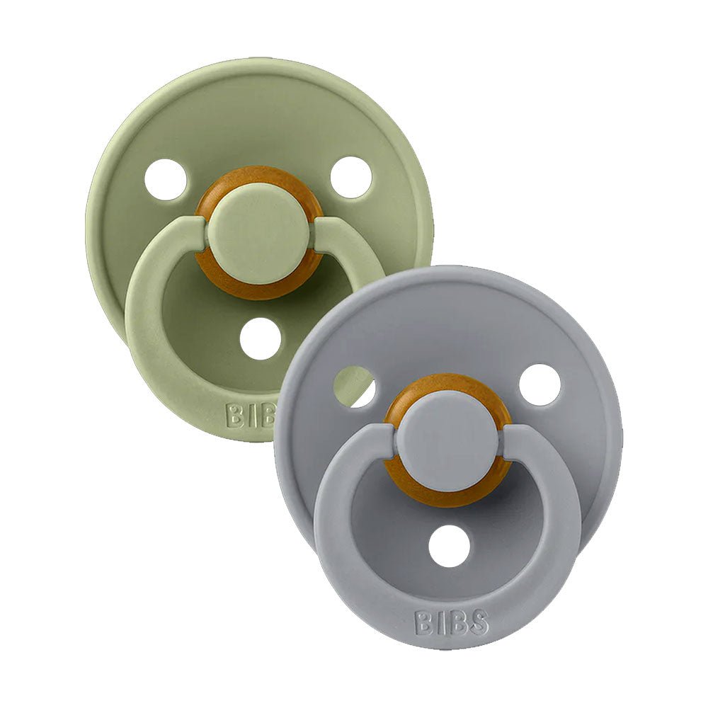 Two baby pacifiers, sage green and light blue with circular orange ring