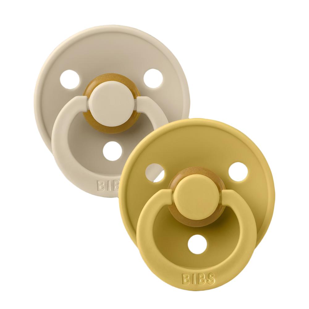 Two pacifiers, one beige and one mustard, each with round shield and vent holes