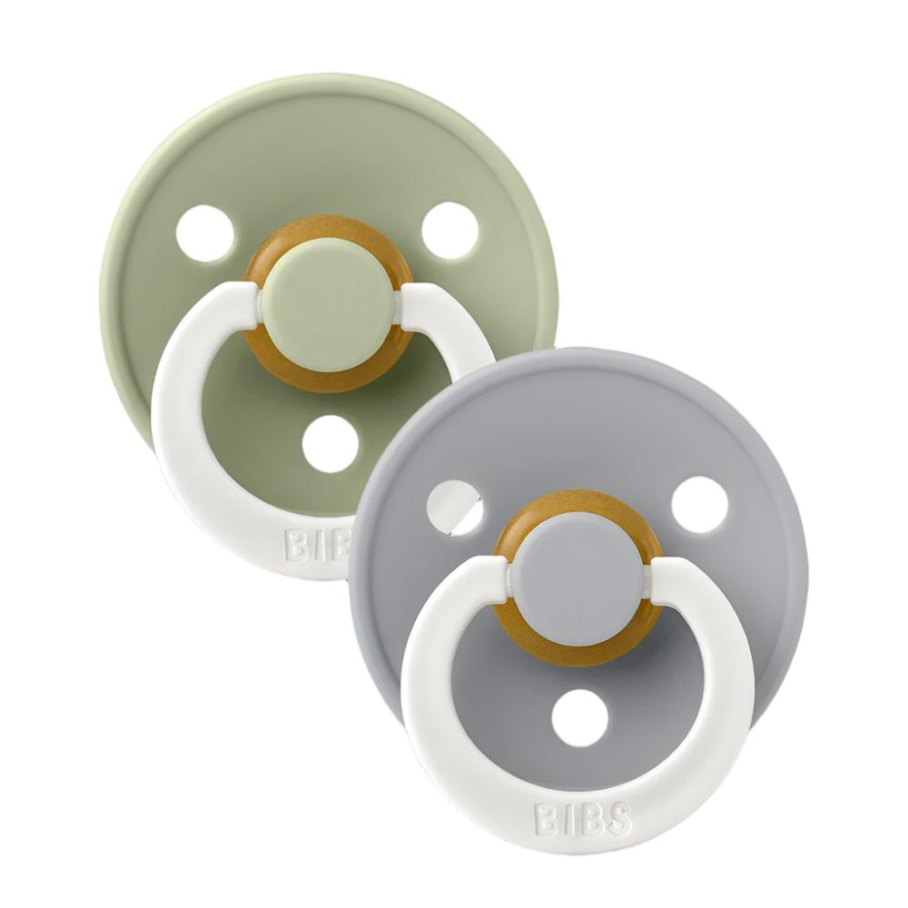 Two pacifiers with white loop handles; sage and light gray shields with warm center