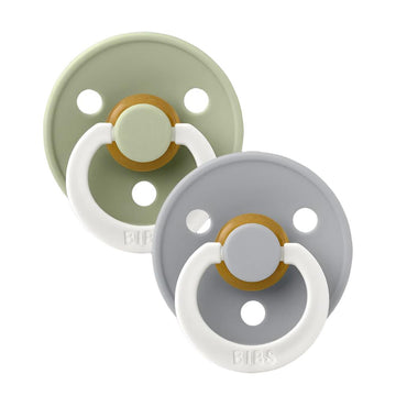 Two pacifiers with white loop handles; sage and light gray shields with warm center