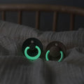 Two pacifiers with dark shields and glowing green rim around the nipple guard